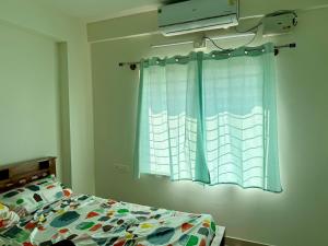 a bedroom with a bed and a window with a curtain at Between Tides nd Toasts Udupi Manipal in Manipal