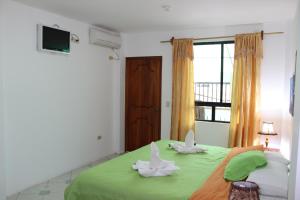 a bedroom with a green bed with two white rabbits on it at The Island Home in Puerto Ayora