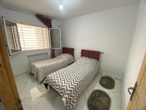 two beds in a small room with a window at Villa Prestige sfax in Sfax