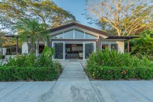 a home with glass doors and plants at The Point 23 At Playa Avellanas in Playa Avellana