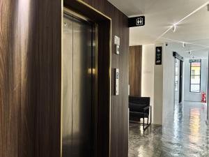 an elevator in an office with a black chair at Muari Boutique Hotel in Muar