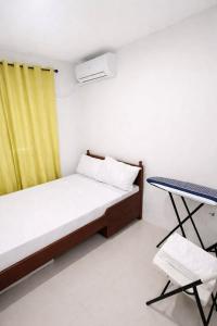 ein kleines Schlafzimmer mit einem Bett und einem gelben Vorhang in der Unterkunft Ben & Ben in San Fernando