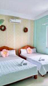 two beds in a bedroom with flowers on the wall at Hotel Kim Ngân Đảo Lý Sơn in Ly Son