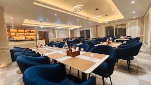 a dining room with tables and blue chairs at Hotel Eastleigh in Ludhiana