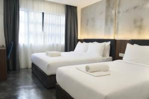 a hotel room with two beds and a window at Muari Boutique Hotel in Muar