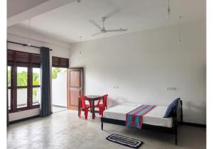 a bedroom with a bed and two red chairs at Thotupola Villa - Mirissa in Mirissa