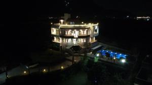 a large white building with lights at night at Cozy Cliff By Marwar Royal in Thūr