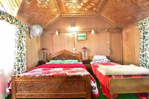 a bedroom with two beds and a wooden ceiling at La Barca Zaindari in Srinagar