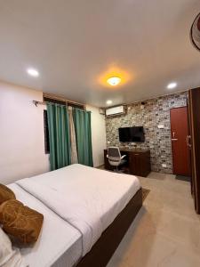 a bedroom with a bed and a desk and a television at Hotel serenity villa in Guwahati