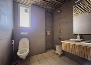 a bathroom with a toilet and a sink and a window at Stays - Golf Course Road in Gurgaon +32 photos
