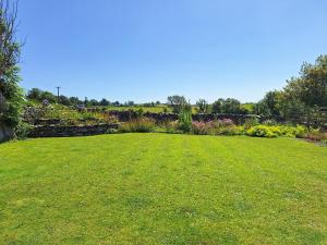 a large grassy yard with a stone wall at Gable End Cottage in Ingleton