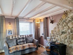 a living room with a couch and a stone wall at Gable End Cottage in Ingleton +10 photos