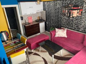a living room with a pink couch and a kitchen at Royal Palace Boutique Otel Boudja in Buca +17 photos