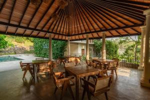 a restaurant with wooden tables and chairs under a roof at Tropical trails by wija house-unawatuna in Unawatuna