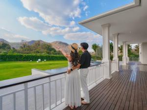 a man and woman standing on the balcony of a house at Solune Khaoyai Pool Villa in Ban Rai Khlong Sai
