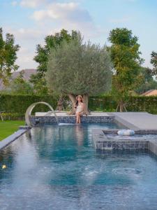 a woman is sitting next to a swimming pool at Solune Khaoyai Pool Villa in Ban Rai Khlong Sai