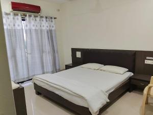a bedroom with a bed with a black headboard and a window at Hotel Sai Palace Executive Lodging in Bīr