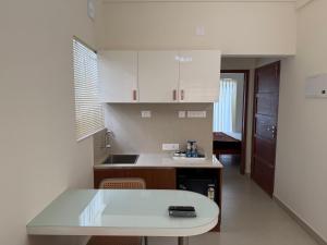 a kitchen with white cabinets and a counter top at Balcony inn in Nedumbassery