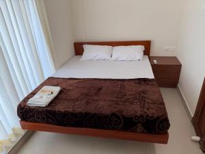 a small bedroom with a bed with a brown blanket at Balcony inn in Nedumbassery