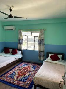 a blue room with two beds and a window at Hotel Marcopolo in Pokhara