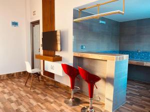 a bar with two red stools in a room at Eastern Heritage Resort in Mymensingh