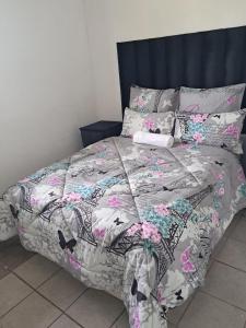 a bed with a comforter and pillows on it at THEMBAGUESTHOUSe in Benoni