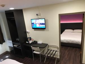 een kamer met een bed, een bureau en een televisie bij L Hotel at 51 Desker in Singapore