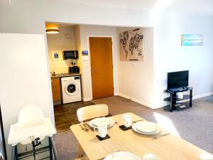 a living room with a table and a kitchen at Parkside Apartment Normanton in Wakefield