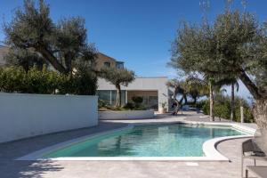 a swimming pool in front of a house with trees at Villa Teresa in Cefalù