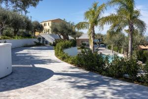 a driveway with palm trees and a house at Villa Teresa in Cefalù