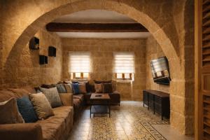 a living room with a large couch and a stone wall at Ta' Frenc Farmhouse in Għarb