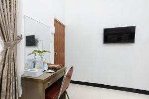 a room with a desk with a tv on a wall at RedDoorz at Batutulis Bogor by House of M in Bogor