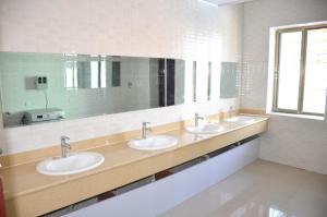 La salle de bains est pourvue de 3 lavabos et d'un grand miroir. dans l'établissement The Silk Road Travelers Hostel, à Zhangye