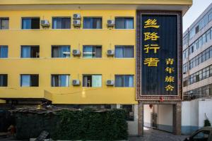 un edificio amarillo con un cartel delante en The Silk Road Travelers Hostel, en Zhangye