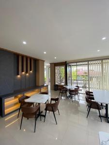 a dining room with tables and chairs and windows at Pavo Guest House in Minangkabau International Airport