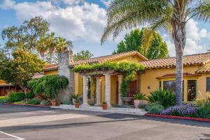 a yellow house with palm trees and a street at Inn Marin and Suites, an Ascend Collection Hotel in Novato