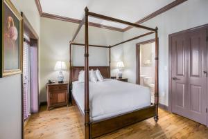 a bedroom with a canopy bed with white sheets at Water Street Hotel & Marina, an Ascend Collection Hotel in Apalachicola