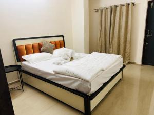 a bed with white sheets and a dog laying on it at The Hampiness in Hospet