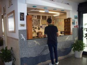 リド・ディ・イエゾロにあるHotel Portofinoの店のカウンターに立つ男