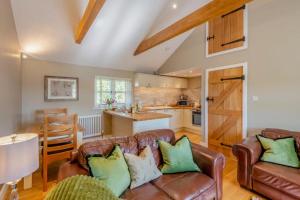 a living room with two leather couches and a kitchen at The Gate Lodge - Pet Free - Near Finchingfield & Saffron Walden in Great Sampford