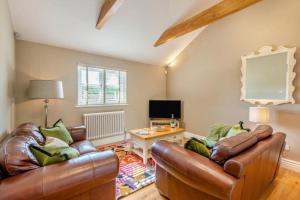 a living room with two leather couches and a television at The Gate Lodge - Pet Free - Near Finchingfield & Saffron Walden in Great Sampford