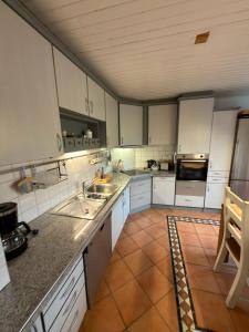 a kitchen with white cabinets and a tile floor at Ferienwohnung Detmold Diestelbruch in Detmold