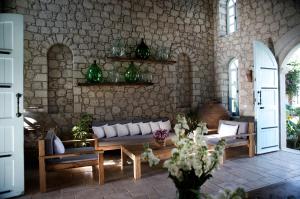 a living room with a couch and chairs and a stone wall at Manastir Alacati Hotel in Alaçatı