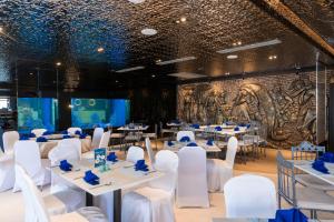 a banquet hall with white tables and chairs and a wall with a mural at Pearl Hotel Phuket in Phuket
