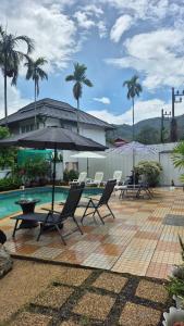a patio with chairs and an umbrella next to a pool at Nur Nur Residence and villa in Surin Beach
