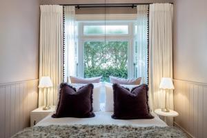 a bed with pillows in front of a window at Seapoint Cottage, Luxury Accommodation in Napier