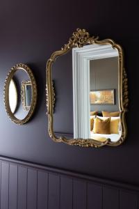 a gold mirror on a wall next to a bed at Seapoint Cottage, Luxury Accommodation in Napier