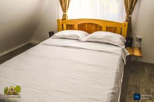 a bed with white sheets and pillows in a bedroom at Căsuța din livadă in Secăria