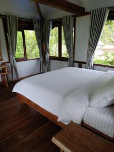 a bedroom with a large white bed with windows at SUMATRA ECORESORT in Bukittinggi