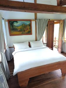 a bedroom with a white bed with a painting on the wall at SUMATRA ECORESORT in Bukittinggi +32 photos